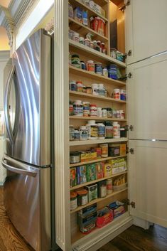 an organized pantry in the middle of a kitchen with stainless steel refrigerator and wood flooring