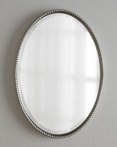 a round mirror hanging on the wall with beaded trim around it's edge