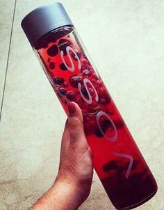 a person holding a water bottle with berries on it and the words go written on it