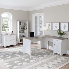 a computer desk sitting on top of a wooden floor next to a white book shelf