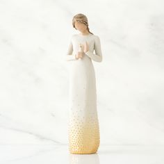 a white figurine with gold dots on it's body and hands in the air