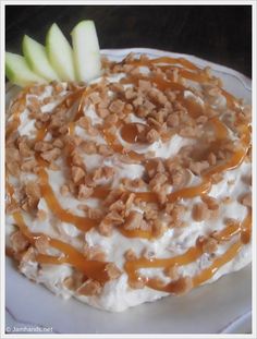 a white plate topped with an oatmeal covered in nuts and apple slices