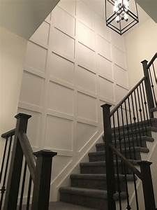 a stair case next to a chandelier in a room with white walls and black railings