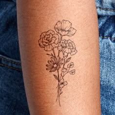 a woman's arm with a tattoo on it that has flowers drawn on it