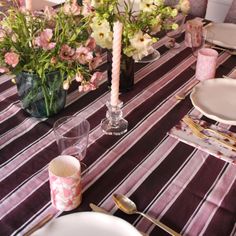 the table is set with pink and white flowers in vases, silverware, and candlesticks