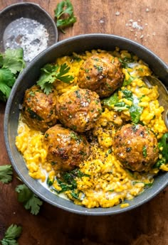 meatballs and rice in a skillet on a wooden table with parsley garnish