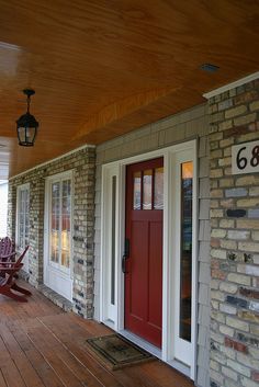 a porch with chairs and a red door