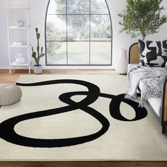 a white rug with black letters on it in front of a large window and potted plant