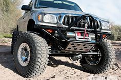 the front end of a silver truck with large tires