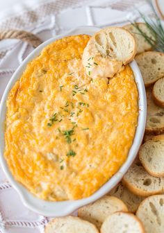 a white bowl filled with bread and dip on top of a table next to crackers