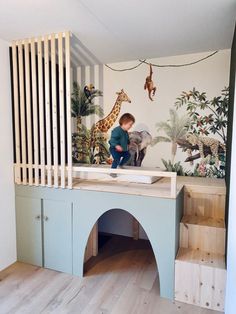 a young boy is playing in his playroom with giraffes on the wall