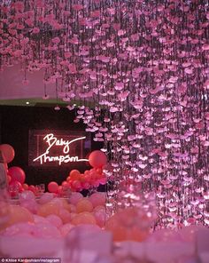 pink balloons and streamers hanging from the ceiling in a room with a neon sign