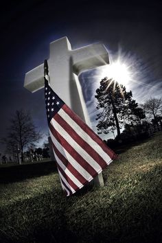 an american flag laying in front of a cross