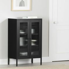 a black cabinet sitting next to a white door in a room with a rug on the floor