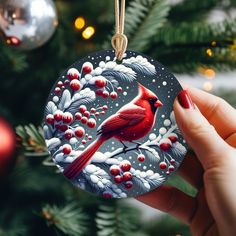 a hand holding a christmas ornament with a cardinal on it