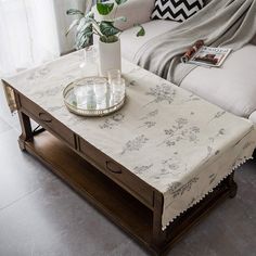 a living room with a couch, coffee table and potted plant on top of it