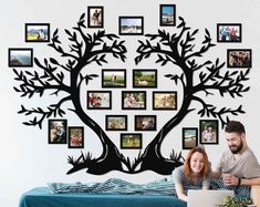 a man and woman sitting in front of a tree with pictures on it