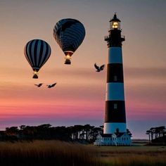 two hot air balloons flying over a lighthouse at sunset with seagulls in the foreground