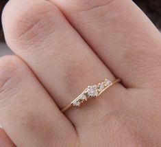 a woman's hand with a gold ring on it and three diamonds in the middle