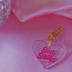 a pink heart shaped keychain with the words go big smile on it's side