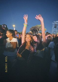 two women standing in front of a crowd with their hands up