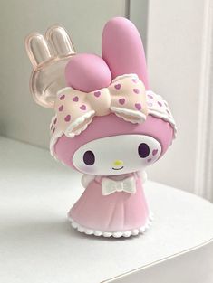 a pink and white hello kitty figurine sitting on top of a counter next to a mirror