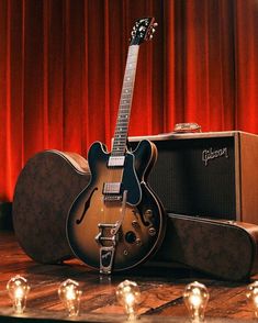 an electric guitar sitting on top of a wooden table next to a speaker and amp