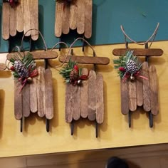 four wooden pegs with pine cones and bows on them hanging from the side of a wall