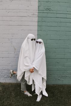 two people dressed in white standing next to each other with their hands wrapped around them