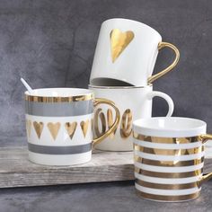 gold and white coffee mugs are stacked on top of each other with hearts painted on them