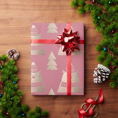 a gift wrapped in blue wrapping paper with a red bow on top and pine cones around it