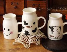 three milk jugs with faces painted on them are sitting on a table next to a doily