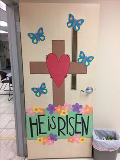 a door decorated with flowers and a cross that says he's risen on it