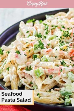 seafood pasta salad in a black bowl on a red tablecloth with text overlay