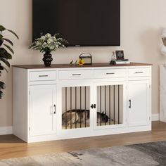 a white dog kennel in front of a flat screen tv mounted on a wall