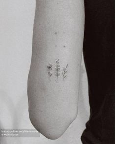 a woman's arm with three small flowers on the back of her left arm