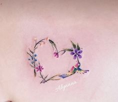 a heart made out of flowers on the back of a woman's stomach