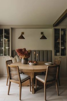 a dining room table with chairs and a vase filled with flowers sitting on top of it