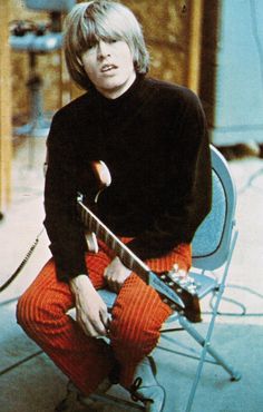 a person sitting on a chair with a guitar in their lap and wearing orange pants