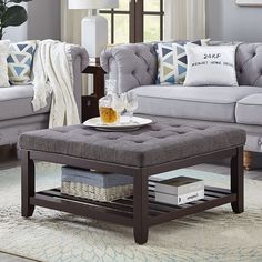 a living room with grey couches and white pillows on the coffee table in front of it