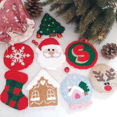 crocheted christmas ornaments are arranged on the floor next to a fir tree and pine cone