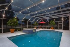 an indoor swimming pool surrounded by glass walls and ceiling lights, with seating area next to it