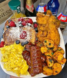 a white plate topped with sausages, french toast and other breakfast foods next to drinks