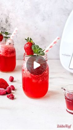 two mason jars filled with raspberry lemonade and topped with fresh strawberries