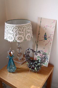 a table with a lamp, vase and painting on it next to a small bird figurine