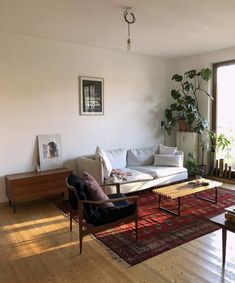 a living room filled with furniture next to a window covered in plants and potted plants