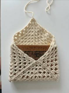 a crocheted object hanging from a string on a white surface with other items in the background