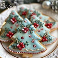 three decorated cookies on a plate with holly and mistlet decorations in the shape of christmas trees