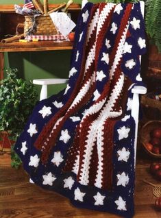 an american flag crocheted afghan sits on a chair in front of a potted plant