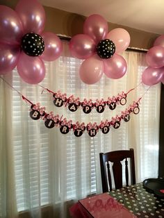 balloons and streamers are hanging from the ceiling in front of a dining room table